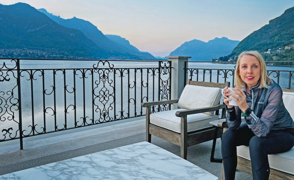 Tracey Pinfold, founder of Exercise Prescription, sitting by a lakeside terrace.