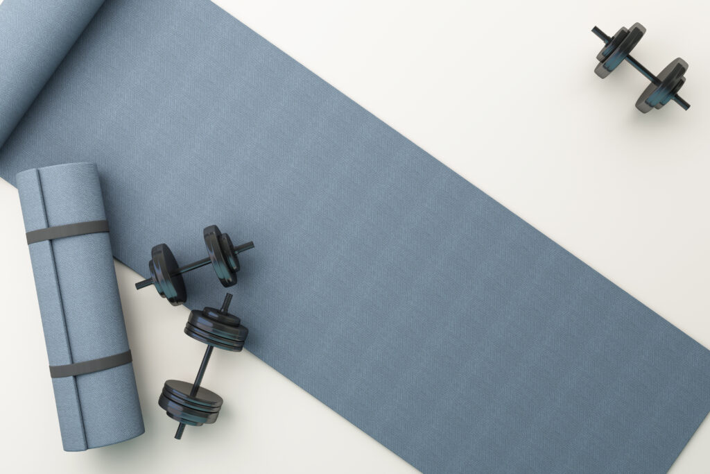 Yoga mat and dumbbells arranged on a fitness mat for a home workout.