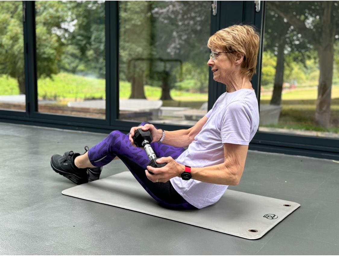 Client performing a seated dumbbell exercise during a personal training session.