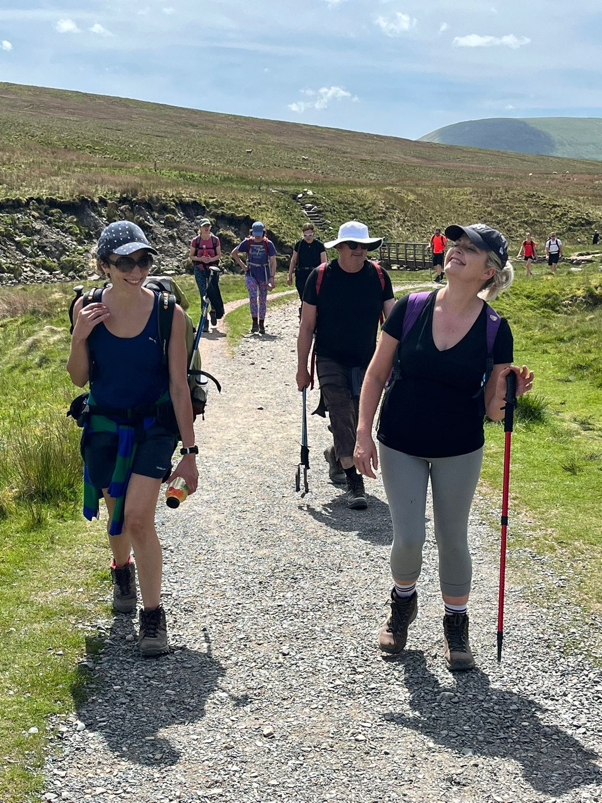 Karima Ngaage walking with a group along a stony path in open hill country