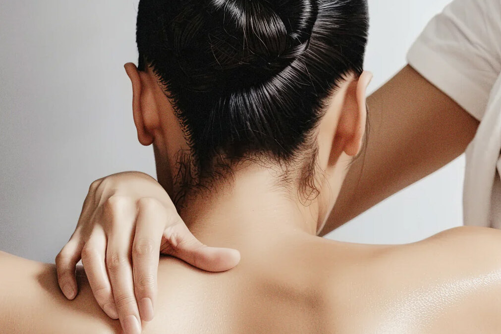 A hand resting on the neck and shoulder, illustrating manual lymphatic drainage.