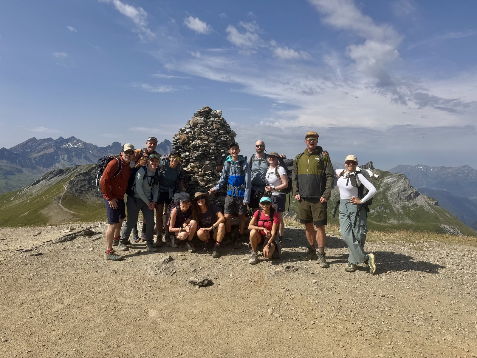 The walking group gathered around a stone cairn at the top of a col on the Tour du Mont Blanc